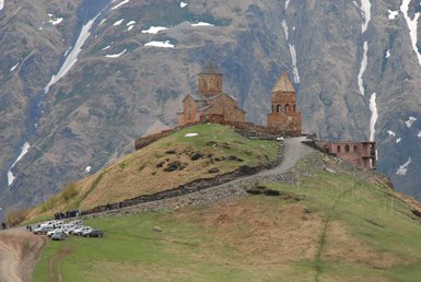 Die majestätische Gergeti-Kirche thront auf einem Hügel, umgeben von beeindruckenden Bergen und schneebedeckten Gipfeln.
