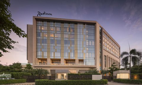 Das moderne Radisson Hotel in Delhi zeigt eine elegante Fassade mit großen Fenstern und einem einladenden Eingangsbereich.