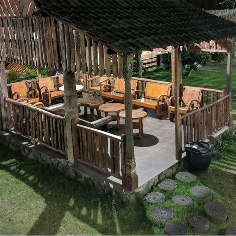 Ein rustikales Holzhaus mit einer gemütlichen Sitzecke, umgeben von grünem Gras und sanfter Beleuchtung in der Nacht.