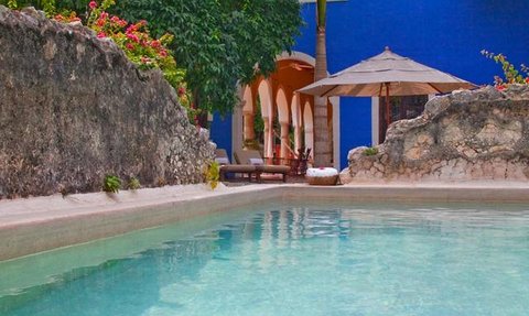 Ein ruhiger Poolbereich mit klarem Wasser, umgeben von üppigem Grün und bunten Blumen, ideal zum Entspannen.