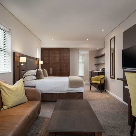 Ein modernes Hotelzimmer mit einem großen Bett, einer gemütlichen Couch und einem Schreibtisch, ideal für Entspannung.