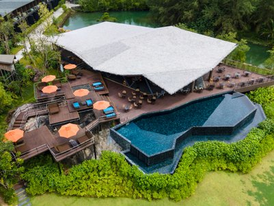 Ein stilvolles Resort mit einem Pool, umgeben von üppigem Grün und gemütlichen Liegen unter orangefarbenen Sonnenschirmen.