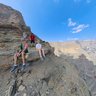Familie macht eine Pause auf einem Felsen und blickt über die beeindruckende Schlucht des Jebel Shams – Oman mit Kindern