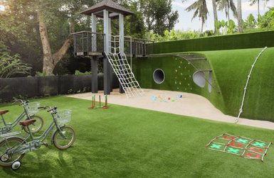 Ein farbenfroher Spielplatz mit einer Rutsche, Kletterwand und Spielzeug auf grünem Rasen, ideal für Kinder zum Spielen.