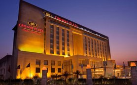 Das Crowne Plaza Hotel in Neu-Delhi erstrahlt in warmem Licht, während der Abendhimmel in sanften Farben leuchtet.