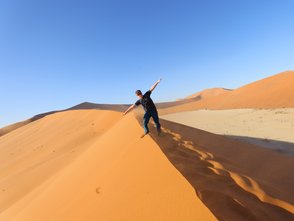 Ein Junge steht auf dem Kamm einer Sanddüne in der Wüste - Namibia Urlaub mit Kindern