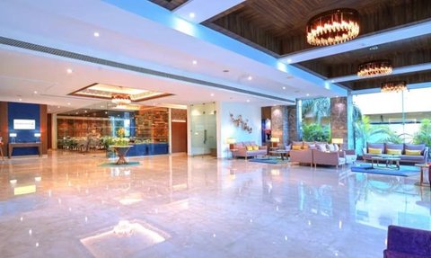 Ein eleganter Hotellobby mit glänzendem Boden, modernen Möbeln und stilvollen Kronleuchtern, die eine einladende Atmosphäre schaffen.