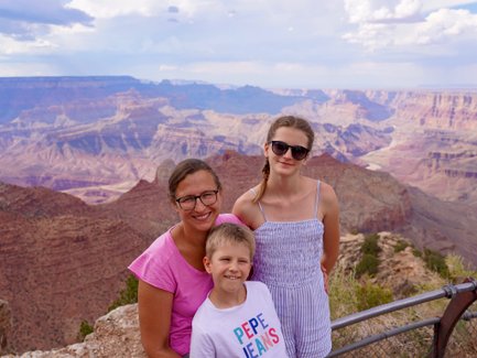 Eine Familie posiert am Grand Canyon, umgeben von beeindruckenden Felsformationen und einer weiten Landschaft.