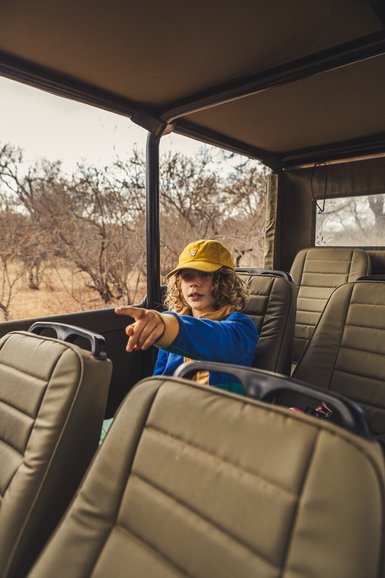 Junge sitzt im Jeep während einer Safari in der Kubu Safari Lodge – Südafrika mit Kindern
