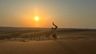Mädchen beim Handstand in der Wüste Omans im Sonnenuntergang – Oman Familienreise