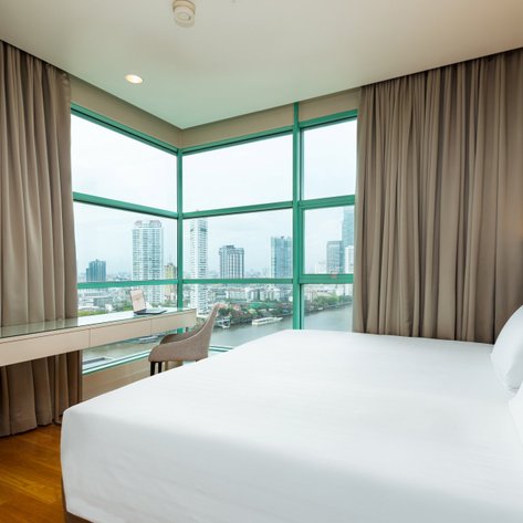 Ein modernes Hotelzimmer mit einem großen Fenster, das einen Blick auf die Stadt und den Fluss bietet.