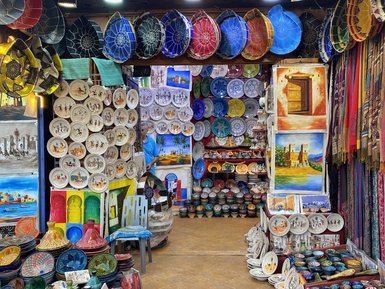 Bunte Töpferwaren und Teller sind in einem lebhaften Souk ausgestellt, umgeben von handgefertigten Kunstwerken.