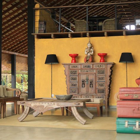 Ein stilvolles Interieur mit einem kunstvoll geschnitzten Schrank und bunten Koffern, das eine einladende Atmosphäre schafft.