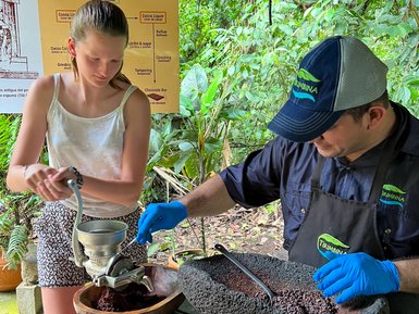 Mädchen und Einheimischer stellen Schokolade bei der Schokoladentour im La Tirimbina Reservat her – Costa Rica mit Kindern