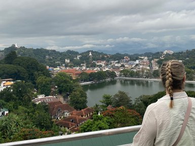 Teenagerin steht auf einem Aussichtspunkt und blickt über die Stadt Kandy – Sri Lanka Reise mit Kindern