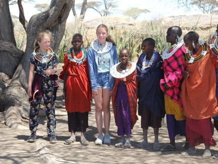 Kinder aus Reisegruppe posieren gemeinsam mit einer Massai-Familie – Tansania Familienreise