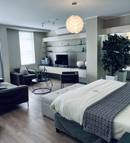 Ein modernes Zimmer mit einem großen Bett, einem stilvollen Tisch und einer gemütlichen Sitzecke, die einladend wirkt.