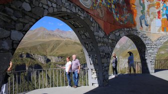 Eine Gruppe von Touristen steht auf einer Aussichtsplattform mit Blick auf die majestätischen Berge im Hintergrund.