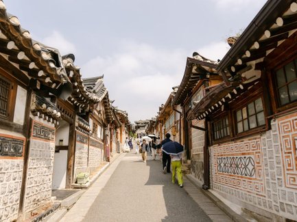 Eine belebte Straße im Bukchon Hanok Village, gesäumt von traditionellen koreanischen Häusern mit charakteristischen Dächern.