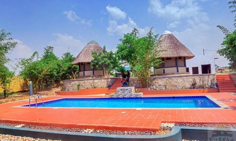 Ein einladender Pool umgeben von üppigem Grün und traditionellen Hütten, ideal für entspannende Tage im Freien.