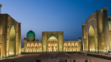 Die beeindruckende Architektur der Registan in Samarkand erstrahlt in warmem Licht, während Menschen die Szenerie genießen.