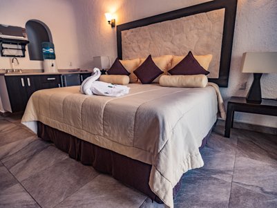 Ein gemütliches Hotelzimmer mit einem großen Bett, dekoriert mit Kissen und einem kunstvoll gefalteten Handtuch auf der Bettdecke.