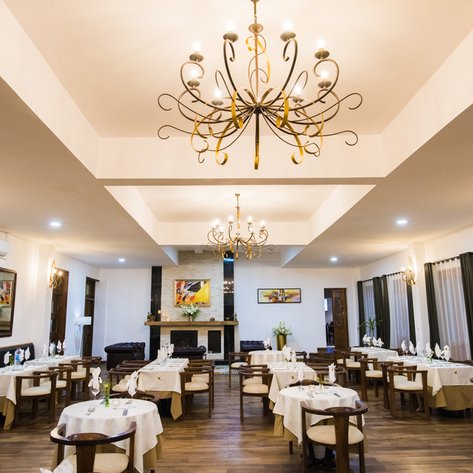 Ein elegantes Restaurant mit stilvollen Tischen, geschmückt mit weißen Tischdecken und kunstvollen Kerzenhaltern.