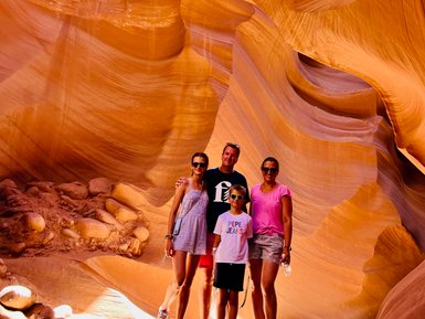 Eine Familie steht in der beeindruckenden Antelope Canyon, umgeben von orangefarbenen Sandsteinformationen und weichem Licht.