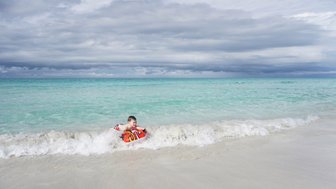 Ein Junge surft auf einer kleinen Welle mit einem Bodyboard