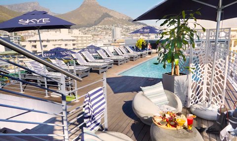 Ein stilvoller Außenpool mit Liegen und Sonnenschirmen, umgeben von einer atemberaubenden Berglandschaft.