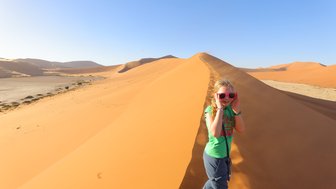 Ein Kind läuft eine Düne hinauf - Namibia Urlaub mit Kindern