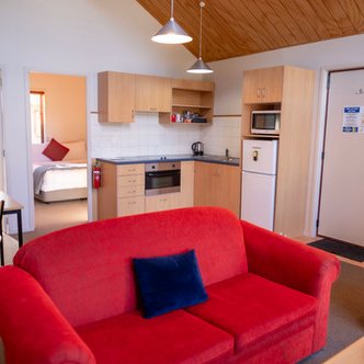 Ein gemütlicher Wohnraum mit rotem Sofa, Esstisch und moderner Küche, ideal für entspannte Aufenthalte.
