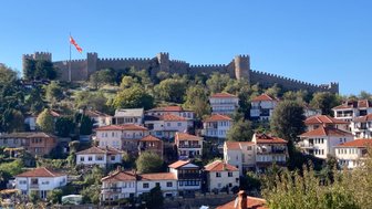 Die alte Stadt Ohrid mit ihren charmanten Häusern und der beeindruckenden Festung im Hintergrund unter strahlend blauem Himmel.