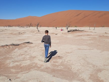 Ein Kind läuft durch eine Wüstenlandschaft - Namibia Reise mit Kindern