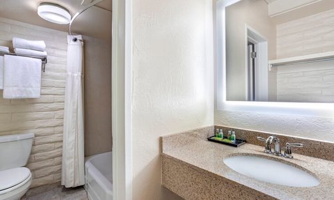 Ein modernes Badezimmer mit einem hellen Spiegel, einer Waschbeckenplatte aus Granit und frischen Handtüchern an der Wand.