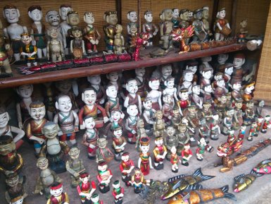 Eine Vielzahl von handgefertigten Holzpuppen in verschiedenen Farben und Stilen, die auf Regalen ausgestellt sind.