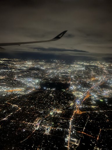 Aus der Vogelperspektive ist die glitzernde Stadtlandschaft von Sydney bei Nacht zu sehen, mit einem dunklen Himmel darüber.