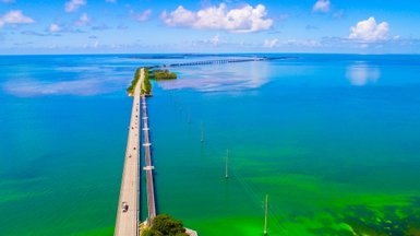Eine malerische Aussicht auf die lange Brücke, die über das türkisfarbene Wasser von Florida führt, umgeben von üppigem Grün.