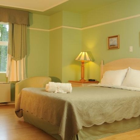 Ein gemütliches Hotelzimmer mit einem großen Bett, sanften grünen Wänden und warmem Licht von zwei Nachttischlampen.