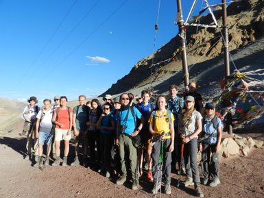 Eine Gruppe von Wanderern posiert fröhlich vor einer beeindruckenden Berglandschaft unter blauem Himmel.