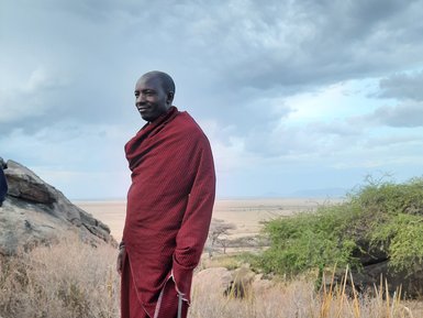 Massai-Mann steht auf einem Kopje des Olduvai Camps – Tansania mit Kindern