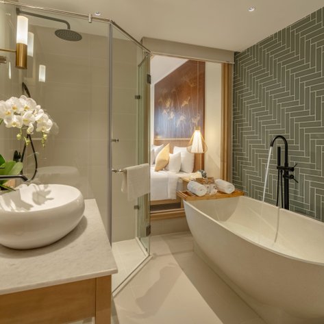 Ein elegantes Badezimmer mit einer freistehenden Badewanne, modernen Armaturen und einer stilvollen Wandverkleidung.