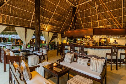 Ein stilvolles Restaurant mit einem hohen Strohdach, eleganten Holzmöbeln und sanfter Beleuchtung für eine entspannte Atmosphäre.