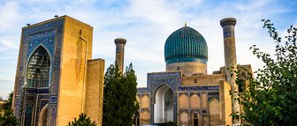 Die beeindruckende Architektur von Samarkand zeigt eine große Kuppel und kunstvoll verzierte Wände unter einem blauen Himmel.
