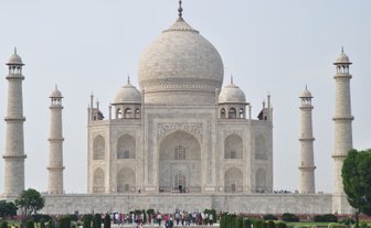 Das majestätische Taj Mahal erhebt sich mit seinen hohen Minaretten und der beeindruckenden Kuppel vor einem klaren Himmel.