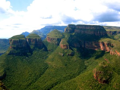 eitläufiger Blick über die grünen Berge der Drakensberge unter klarem Himmel – Südafrika Familienreise