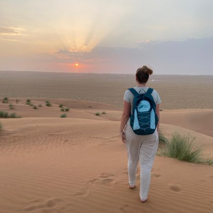 Frau läuft in der Wahiba-Wüste beim Sonnenuntergang – Oman Reise mit Kindern