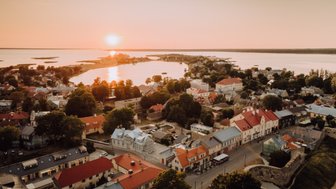 Die malerische Stadt Haapsalu wird von der untergehenden Sonne in warmen Farben beleuchtet, während das Wasser sanft glitzert.