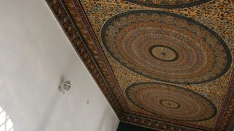 Der kunstvoll gestaltete Deckenbereich zeigt komplexe geometrische Muster in warmen Farben und feinen Details.