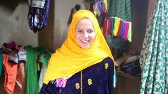 Frau mit gelbem Kopftuch und buntem Gewand in Al Hamra - Oman Familienreise